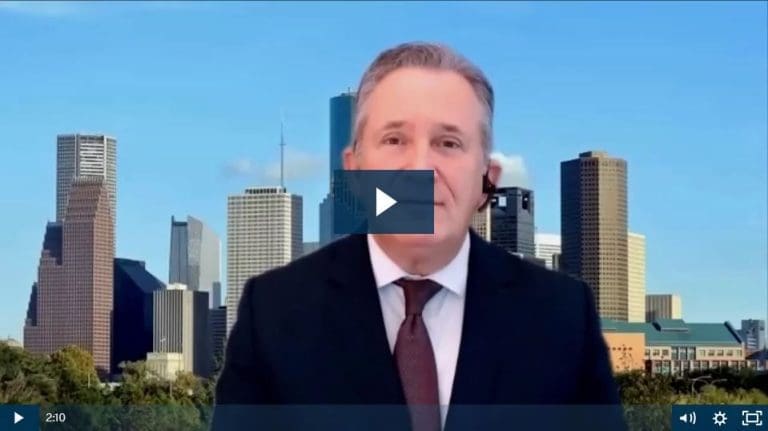 Man in suit with city skyline backdrop for virtual presentation.