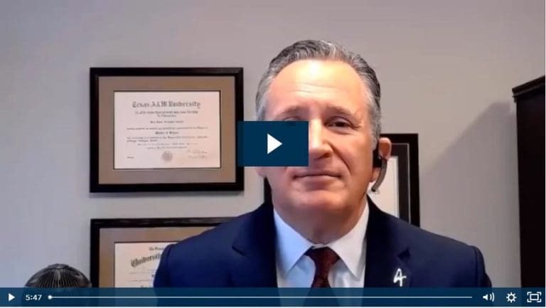 Business professional in video call with university degrees displayed behind.