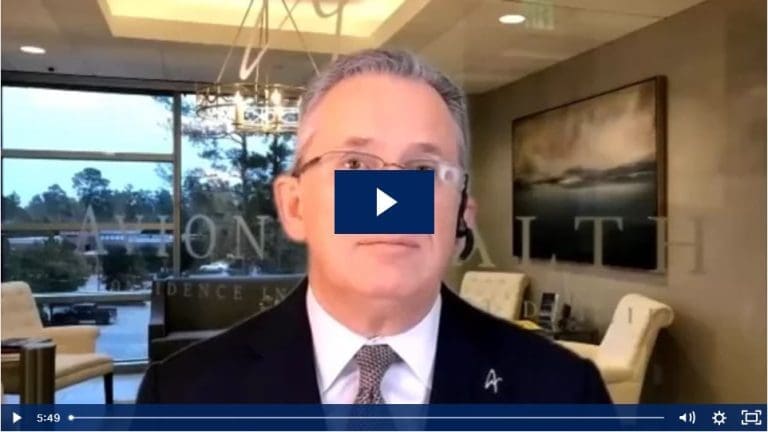 Man in suit during a virtual meeting in a modern office setting.