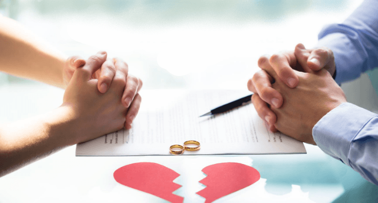 Two people facing each other, divorce papers, wedding rings, broken heart symbol.