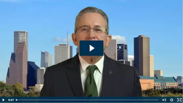 Man in suit speaking with city skyline in background.