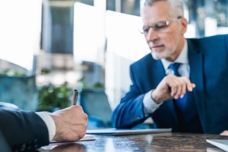 Business meeting with executives signing documents at a desk.