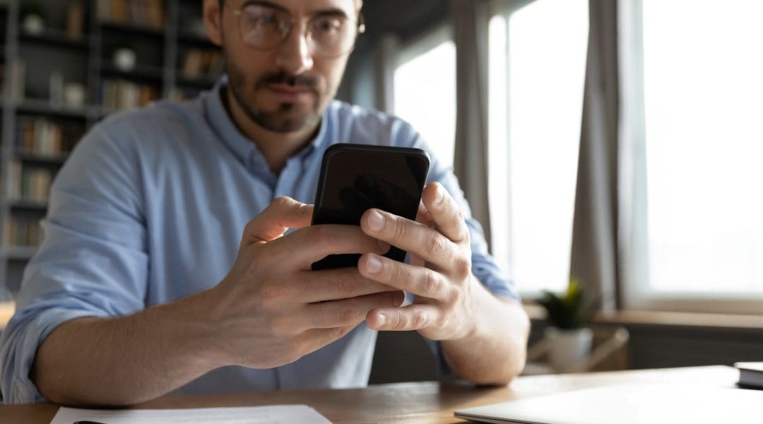 Funding the sale of the business, represented by business person at his desk, looking at his cell phone