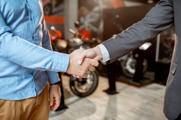 Handshake in motorcycle showroom, business agreement achieved.
