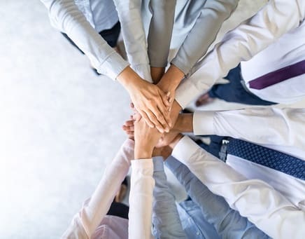 Business professionals stacking their hands ready for a cheer