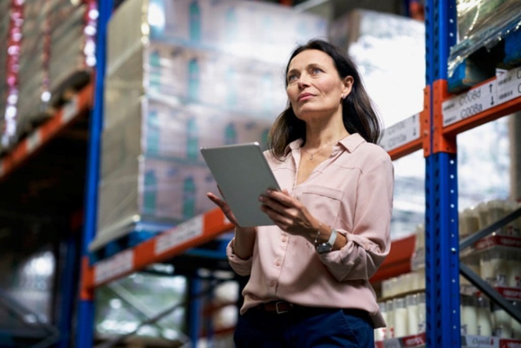 Woman managing inventory with tablet in warehouse.