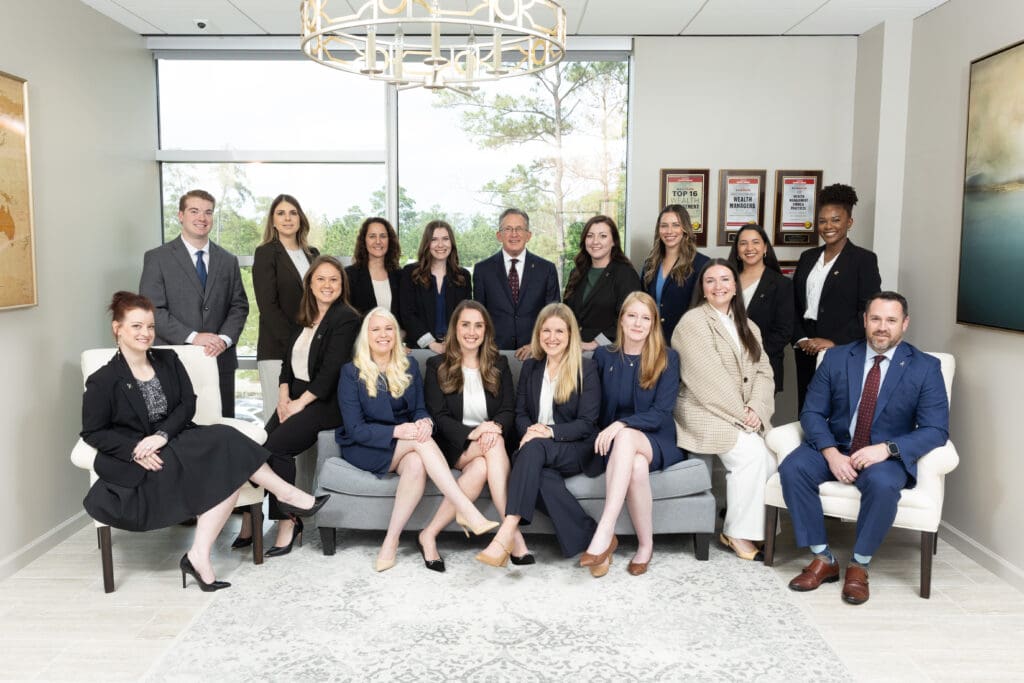 Professional team posing in office with awards on wall behind them.